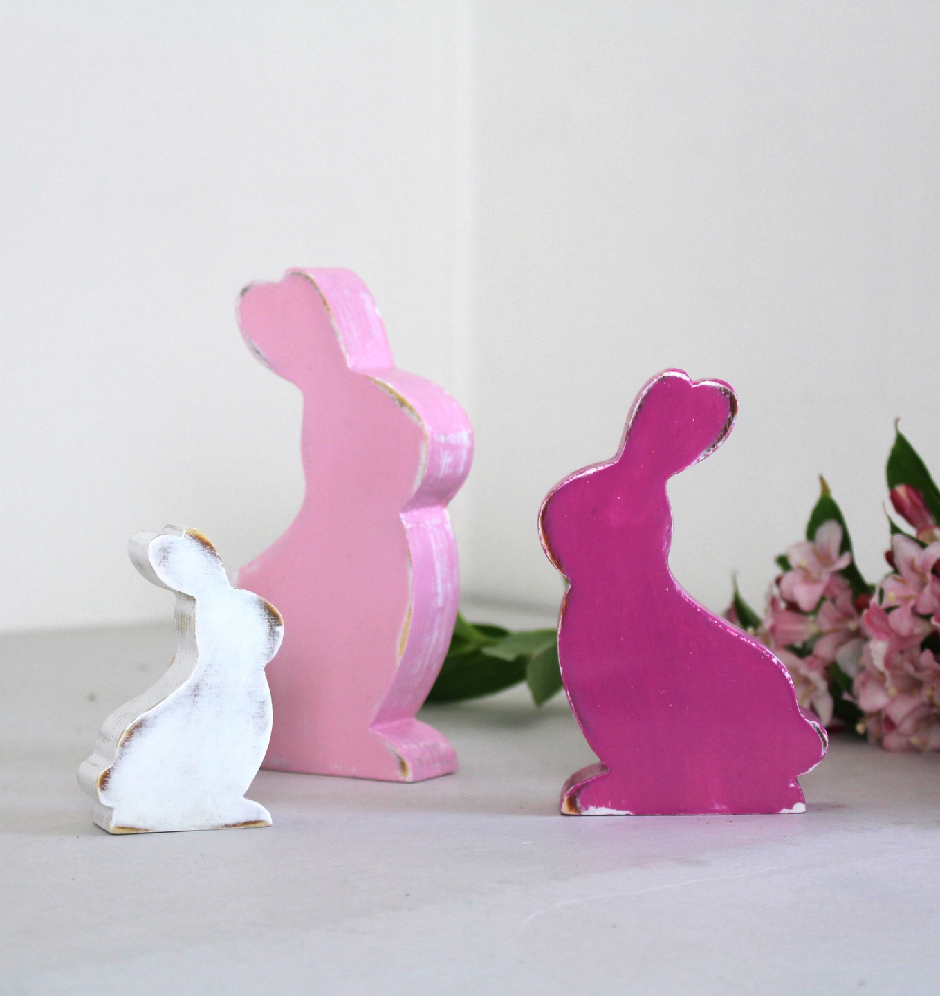 Lot de 3 lapins en bois rose et blanc, patinés.