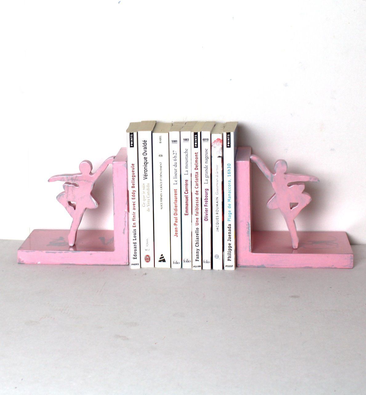Lot de 2 serre-livres danseuses en bois rose patine marquée sur fond gris.